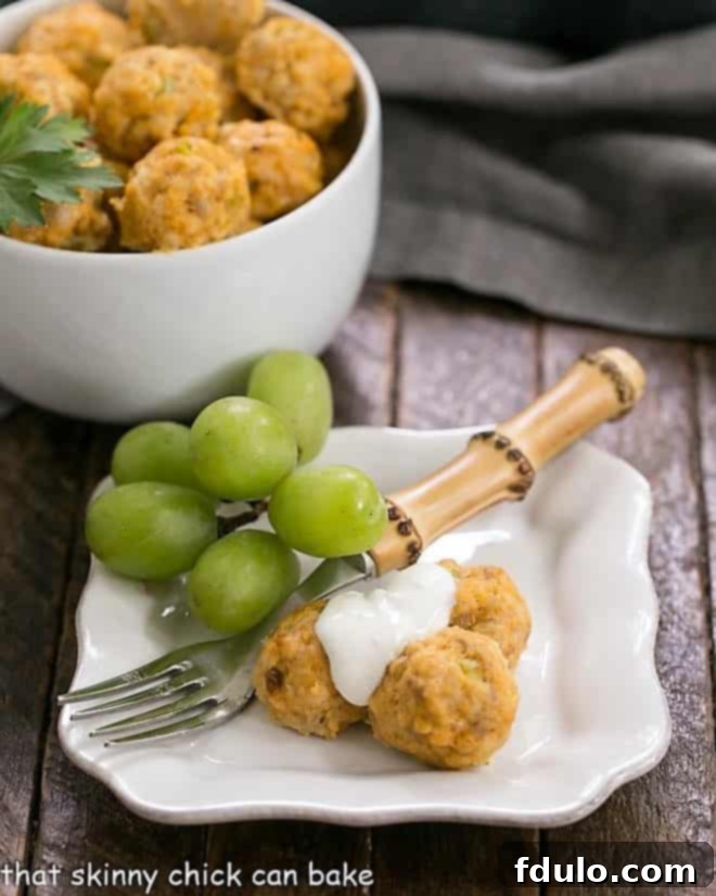 Buffalo Chicken Meatballs on a small white plate topped with blue cheese sauce, garnished with parsley.