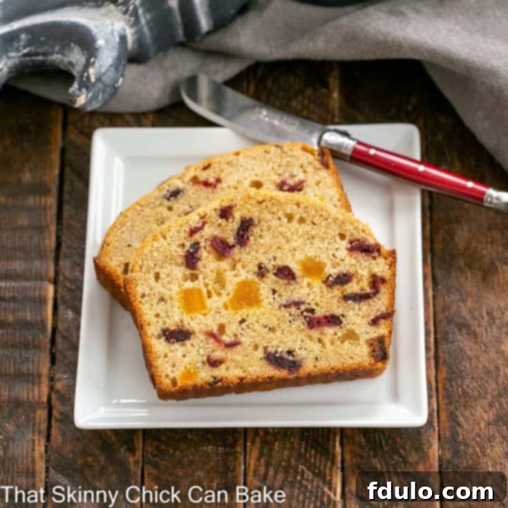 Overhead view of cranberry bread slices on a square white plate with a red handled knife