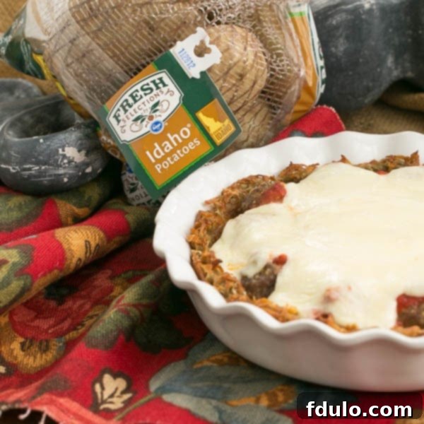 Roman Poutine Gratin 3 A slice of Italian Poutine Pie served on a plate, showcasing the distinct layers of hash brown crust, meatballs, marinara, and melted mozzarella. The textures and colors are inviting and appetizing.