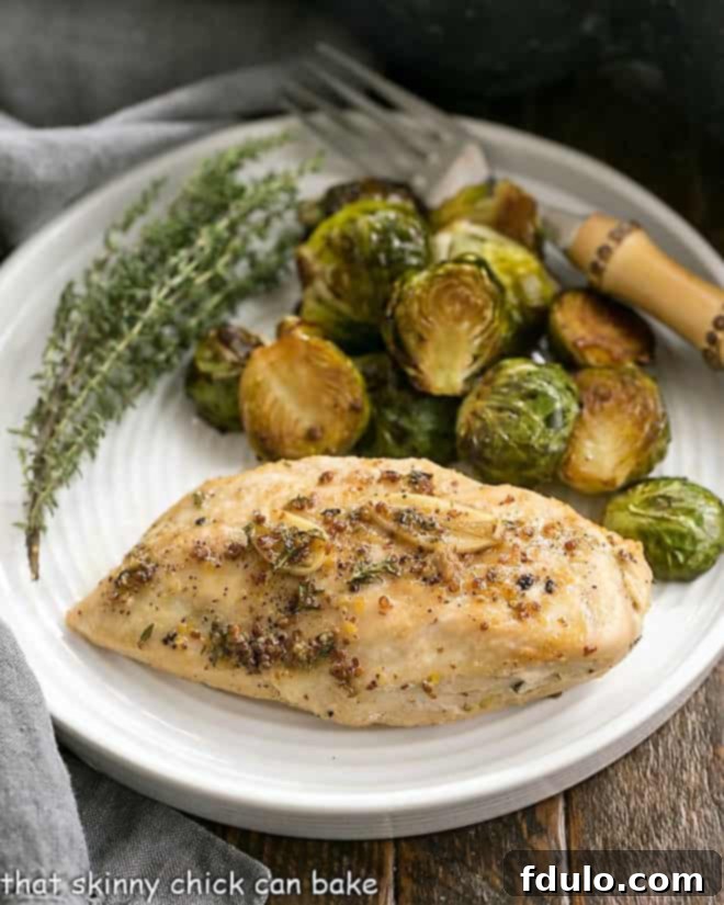 Maple-Glazed Chicken on a dinner plate, garnished with fresh thyme and served with roasted Brussels sprouts