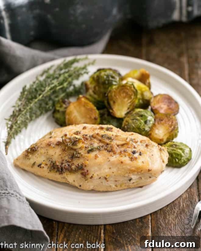 Delicious Mustard Maple Chicken Breast on a white dinner plate, accompanied by vibrant Brussels sprouts