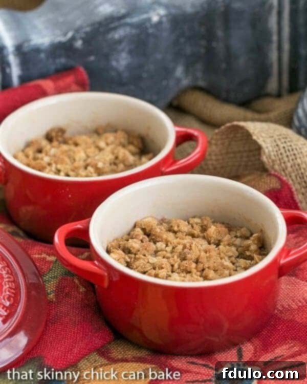 Two small red crocks filled with individual servings of Apple Pear Crisp, ready to be enjoyed.
