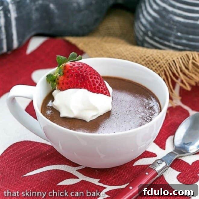 A beautifully set chocolate custard in a white teacup, garnished with a single raspberry and a light dollop of whipped cream, conveying a sense of timeless elegance.