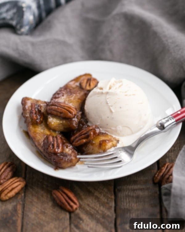 Bananas Foster with a scoop of ice cream on a round white plate, garnished with pecans.