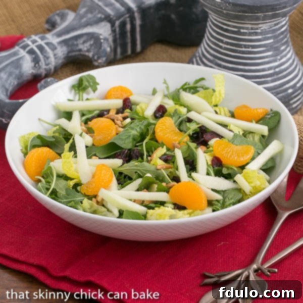 Holiday Lettuce Salad - Easy enough for any time of the year, yet impressive enough for special occasions! A vibrant Holiday Lettuce Salad in a elegant white serving bowl, showcasing fresh greens, red cranberries, orange mandarins, and golden candied almonds.