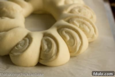 Tea roll dough filled, rolled, and perfectly risen on a parchment-lined baking pan, ready for the oven
