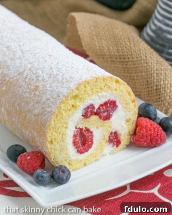 Berry Roulade on a white serving tray with a garnish of fresh berries.
