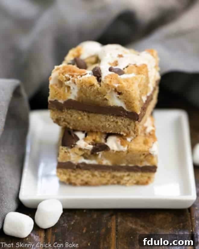 Irresistible S'mores Cookie Bars stacked on a pristine white plate, showcasing their delightful layers of chocolate, marshmallow, and cookie.