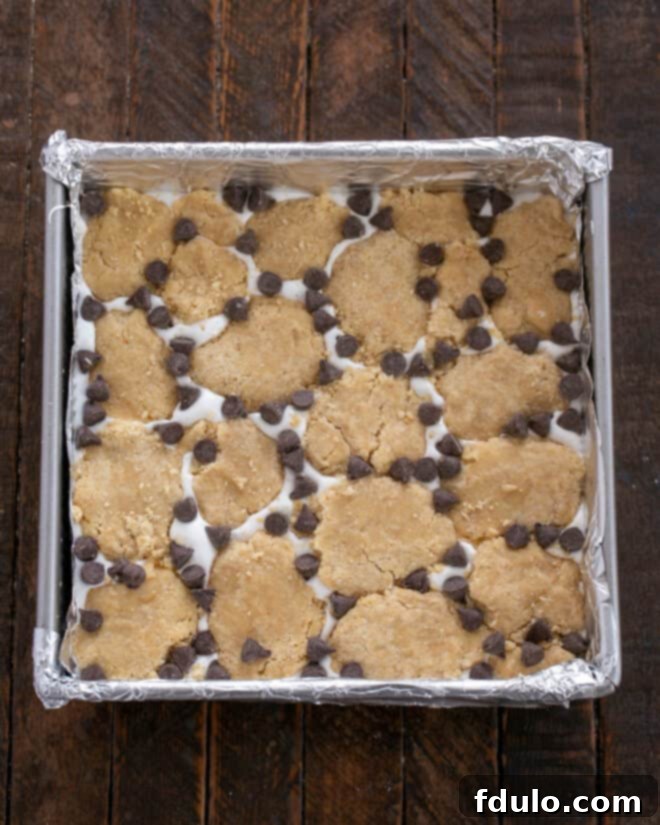 Step 8: Scattering bits of the remaining cookie dough over the marshmallow layer, leaving some peeks of marshmallow, and sprinkling with chocolate chips.