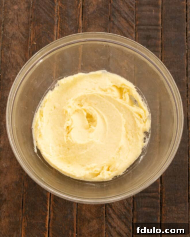 Step 2: Mixing a large egg and pure vanilla extract into the creamed butter and sugar mixture until fully incorporated and smooth.