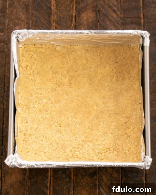 Step 4: Pressing half of the prepared cookie dough evenly into the bottom of a baking pan lined with non-stick foil.