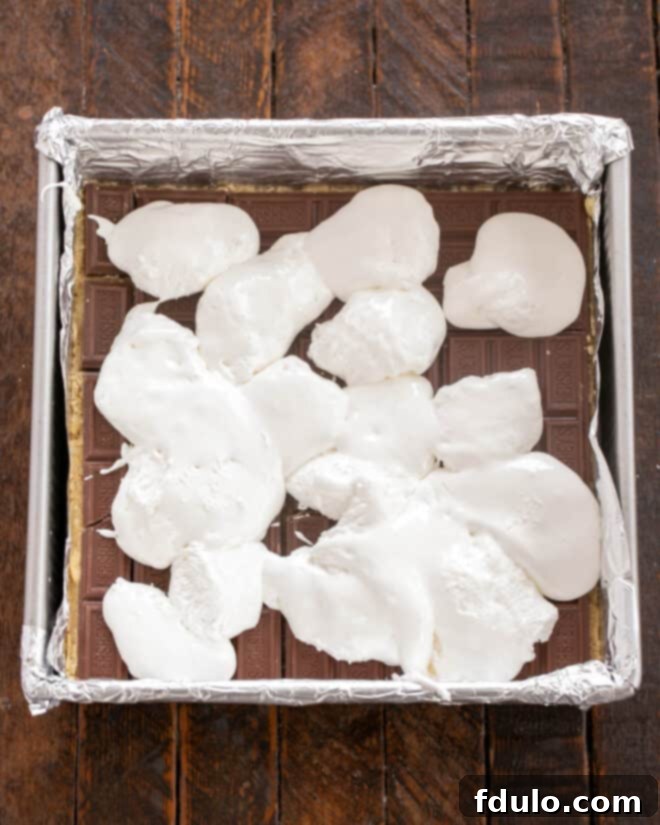 Step 6: Dolloping spoonfuls of sticky marshmallow creme over the layer of chocolate bars.