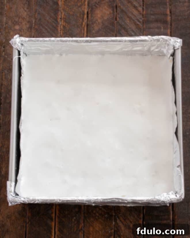 Step 7: Gently spreading the marshmallow creme evenly over the chocolate layer using a damp knife or offset spatula.