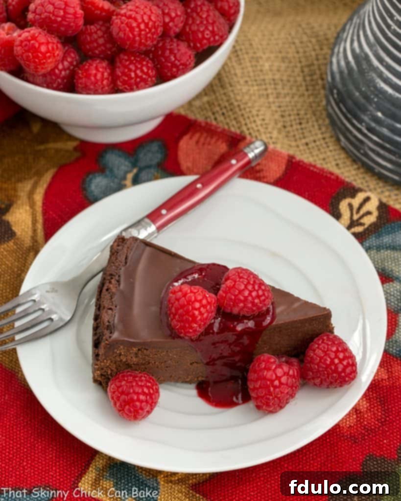 Decadent Flourless Chocolate Torte with Tart Raspberry Sauce 2 Overhead view of a gorgeous gluten-free Chocolate Torte on a pristine white plate, beautifully garnished with swirls of chocolate ganache and a scattering of fresh, ruby-red raspberries.