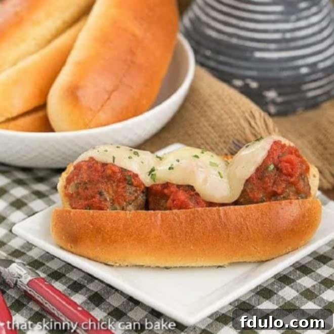 Easy Italian Meatball Subs on a white square plate on a checked napkin, showcasing a perfectly toasted bun, rich marinara, plump meatballs, and melted Provolone cheese.