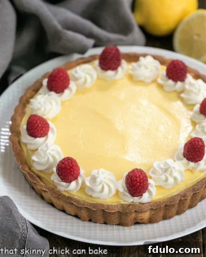 Close-up view of a Creamy Lemon Tart on a white serving dish, highlighting its smooth, glossy surface and perfect crust.