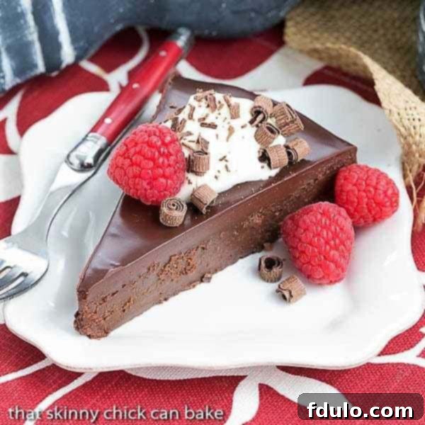La Bete Noire - dark, decadent and out of this world delicious flourless chocolate cake recipe A rich, decadent slice of La Bete Noire on a white plate with a red handle fork.