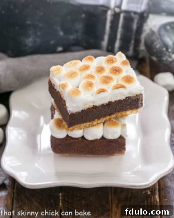 Gooey S'mores Brownies with Graham Cracker Crust 5 two s'mores bars stacked on a square white plate