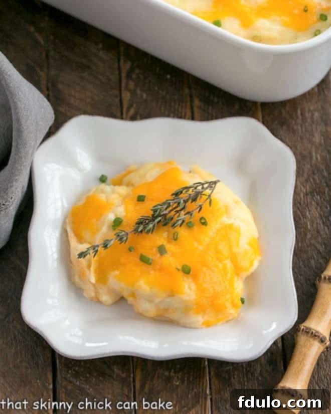 Overhead view of a generous serving of cheesy mashed potato casserole on a square white plate, perfectly golden brown and bubbly, ready to be enjoyed.