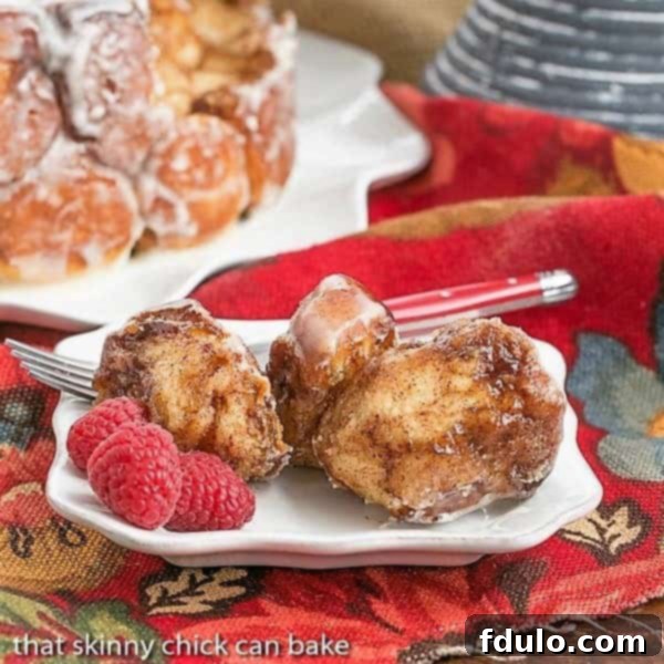 Cinnamon Bubble Roll pieces on a small white plate with fresh raspberries, highlighting the gooey interior