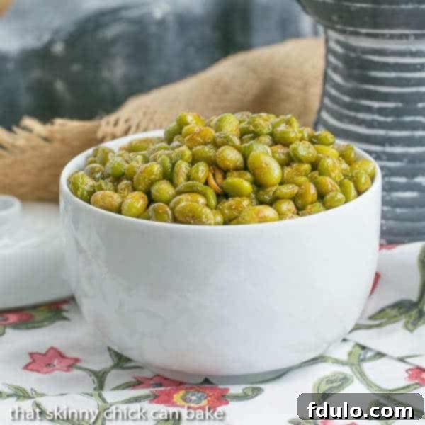 Roasted Creole Edamame in a white bowl, garnished with fresh herbs.