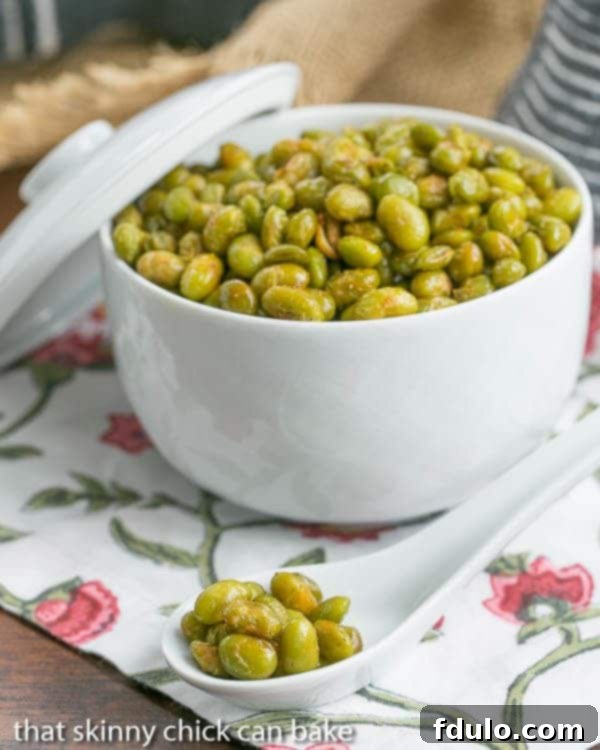 Roasted Creole Edamame in a white ceramic bowl with a spoonful in the foreground, showing the crispy texture.
