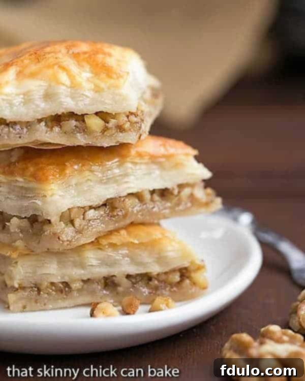 Diamonds of Baklava Recipe stacked on a small white plate, showcasing flaky layers and a rich, golden syrup.