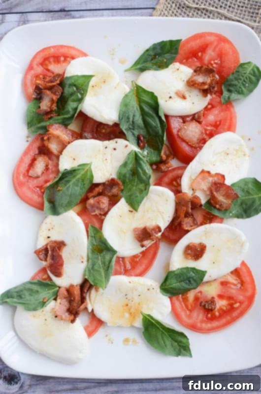 Fresh Caprese Salad with warm bacon dressing, showcasing ripe tomatoes, mozzarella, and basil.