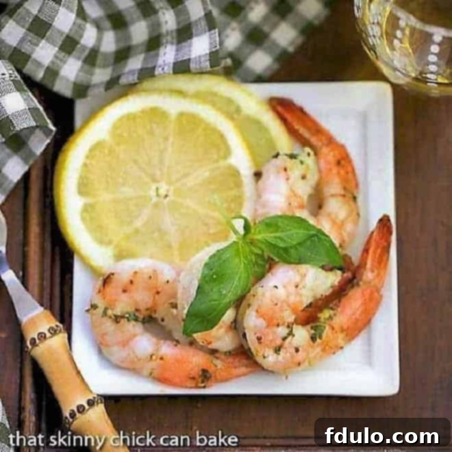 Zesty Grilled Shrimp Scampi 2 Grilled Shrimp Scampi on a square white plate with basil and lemon slices