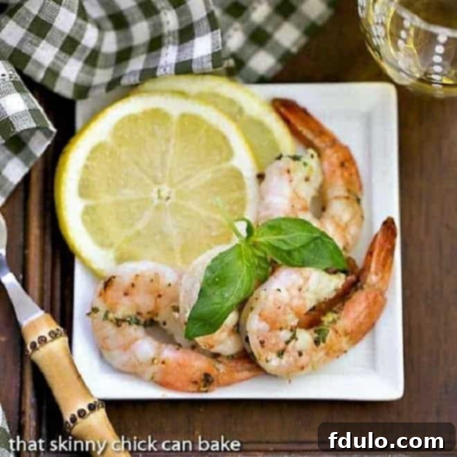 Zesty Grilled Shrimp Scampi 4 Grilled Shrimp Scampi on a square white plate with basil and lemon slices