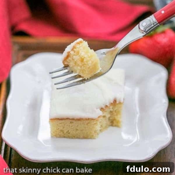 White sheet cake slice with a forkful removed, showcasing its light and fluffy texture.