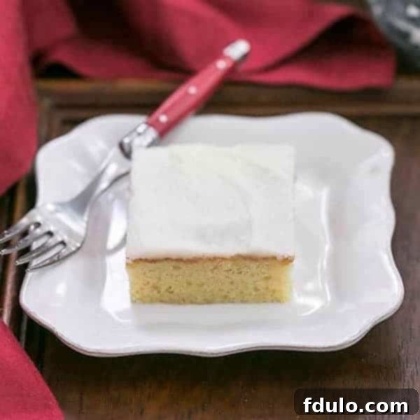 Slice of white sheet cake with a red handled fork