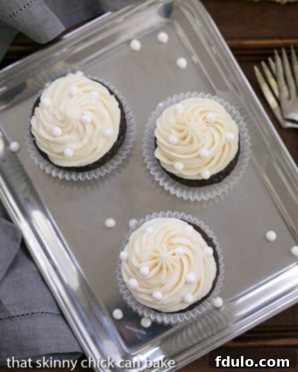 Overhead view of several Vanilla Buttercream Topped Cocoa Cupcakes on a sleek silver tray, showcasing their generous frosting.
