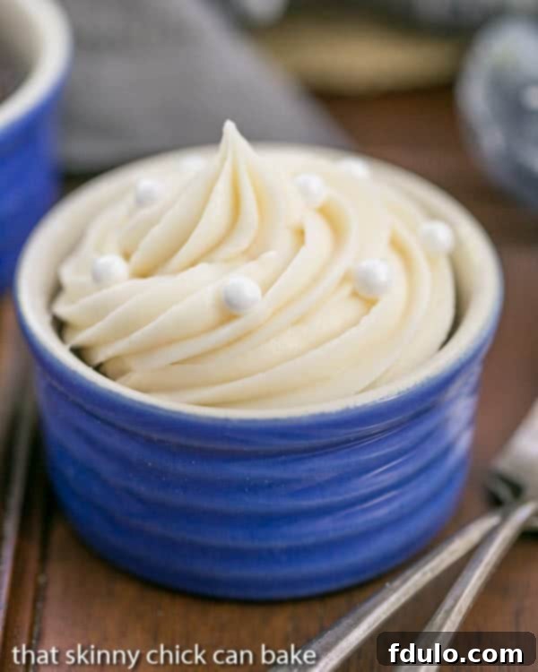 Three decadent Vanilla Buttercream Topped Cocoa Cupcakes nestled in charming blue ramekins, highlighting their inviting appearance.