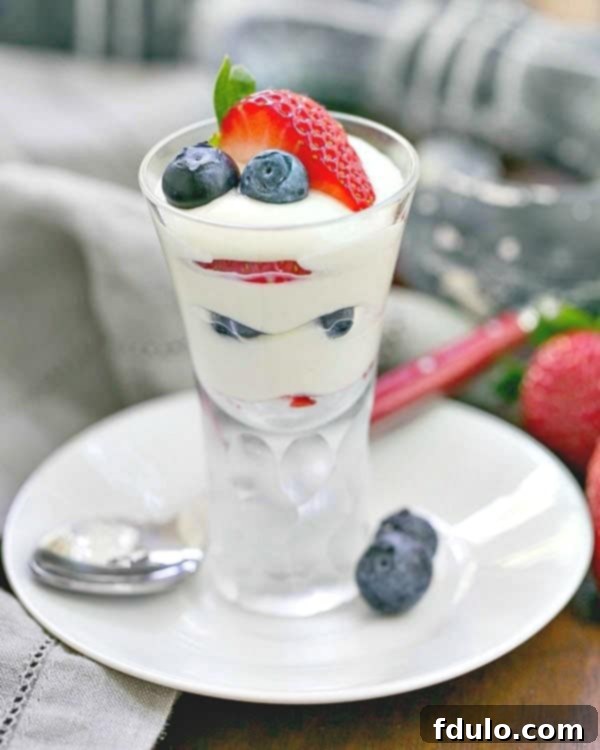 Exquisite White Chocolate Berry Parfaits, layered with fresh strawberries and blueberries, served on a pristine white plate with a red-handled spoon, showcasing a perfect no-bake summer dessert.