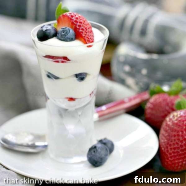 Individual White Chocolate Berry Parfaits elegantly presented, garnished with fresh blueberries and sliced strawberries, highlighting the vibrant colors and layers of this perfect patriotic dessert.
