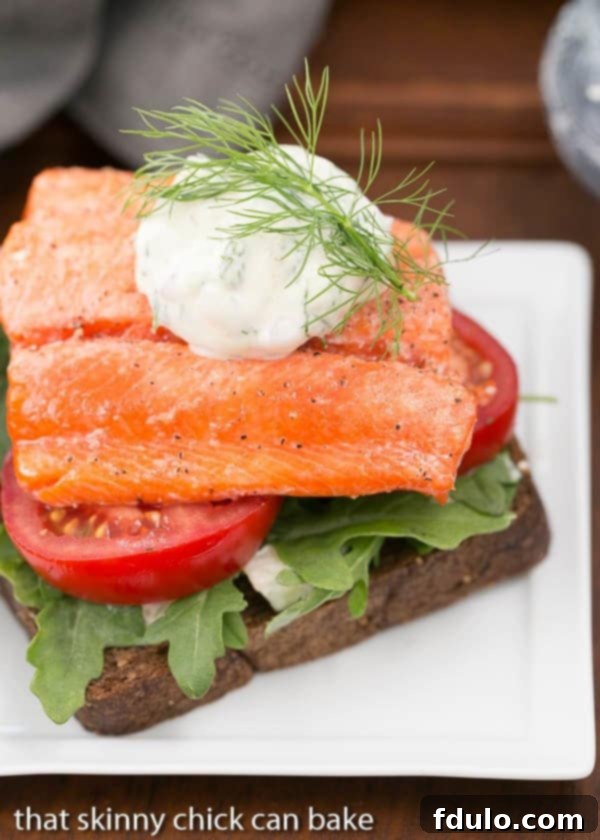 Open-Faced Salmon Sandwiches with Herb Cucumber Relish on a square white plate with a dollop of relish and dill sprig to garnish.