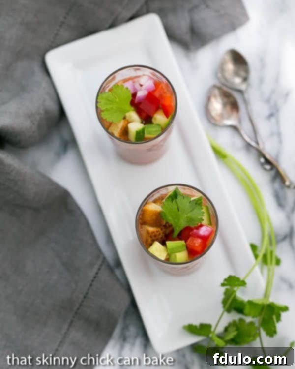 Gazpacho Shooters artfully arranged on a white rectangular tray, garnished with fresh cilantro sprigs for a vibrant display.