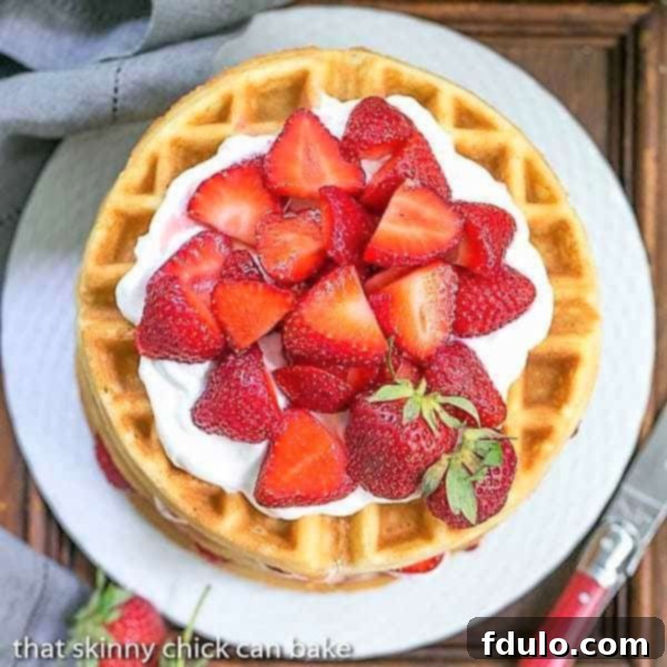 Strawberry Waffle Cake viewed from above on a white cake plate, revealing all the fresh strawberry and cream layers.
