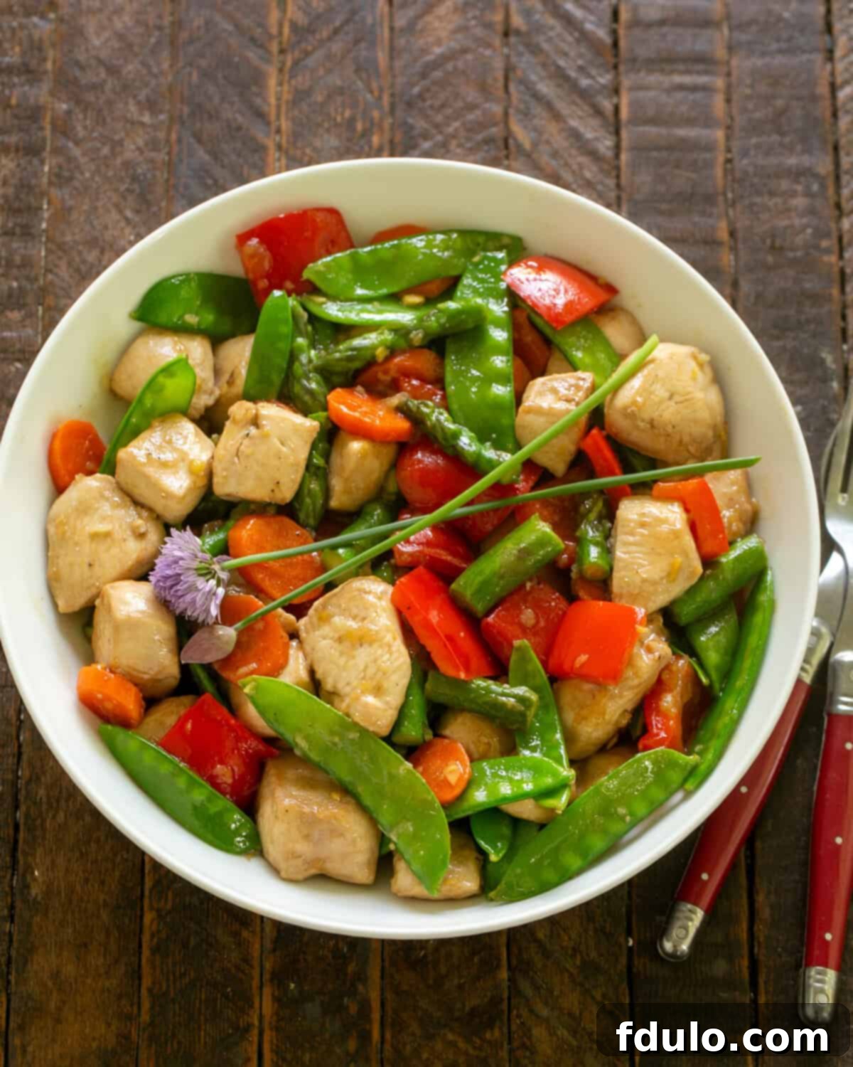 Delicious Chicken Stir Fry in a white serving bowl, garnished and ready to eat.