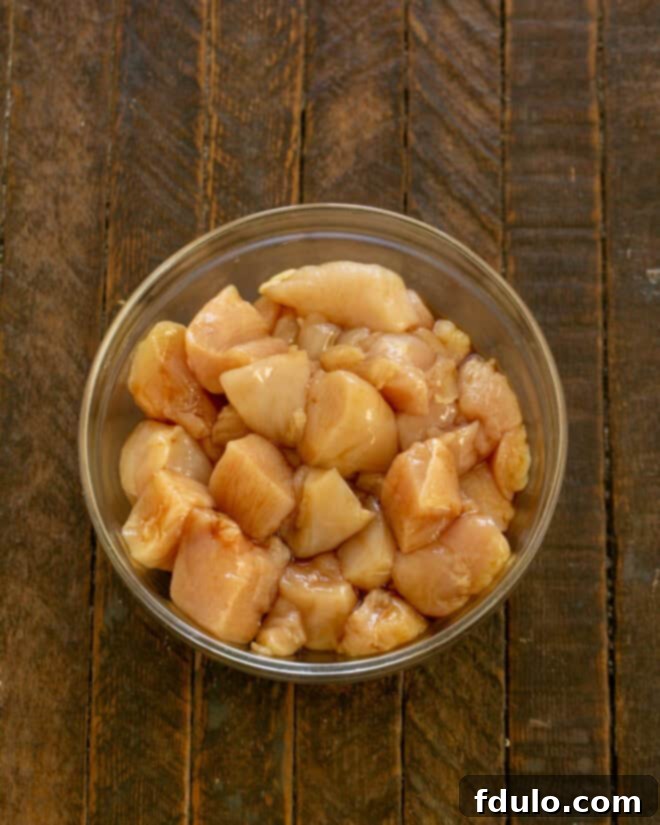 Chicken pieces being tossed with soy sauce and sherry in a bowl for marination.