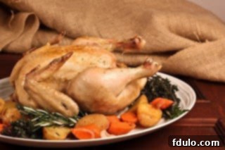 Jacques' Armagnac Chicken 2 Close-up of golden brown Armagnac Chicken served on a white platter with roasted root vegetables and green garnishes