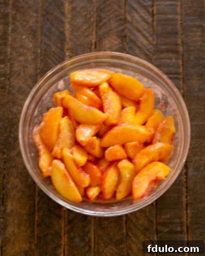 Step 7: Sliced peaches, dry mix, and lemon juice combined in a bowl.
