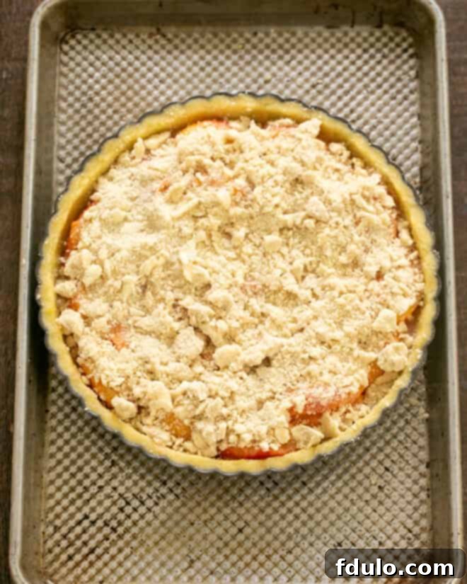 Step 12: Streusel topping sprinkled evenly over peaches in the tart.