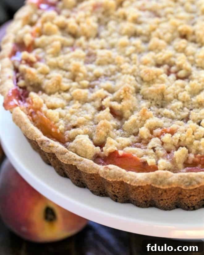 Close view of the edge of a peach dessert recipe, showing the golden crust and bubbling peach filling.