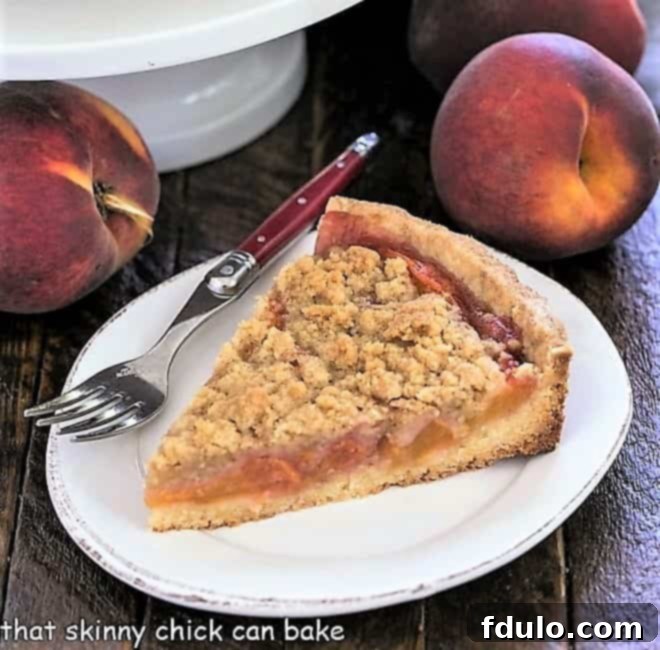 Slice of peach tart recipe on a white ceramic plate, garnished with a sprig of mint.