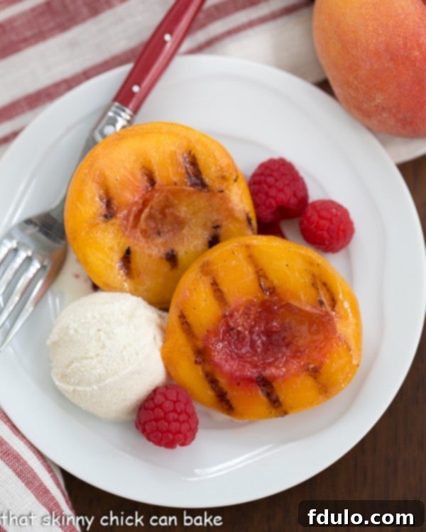 Overhead view of Grilled Peach Melba on a white plate with a fork and scoop of ice cream