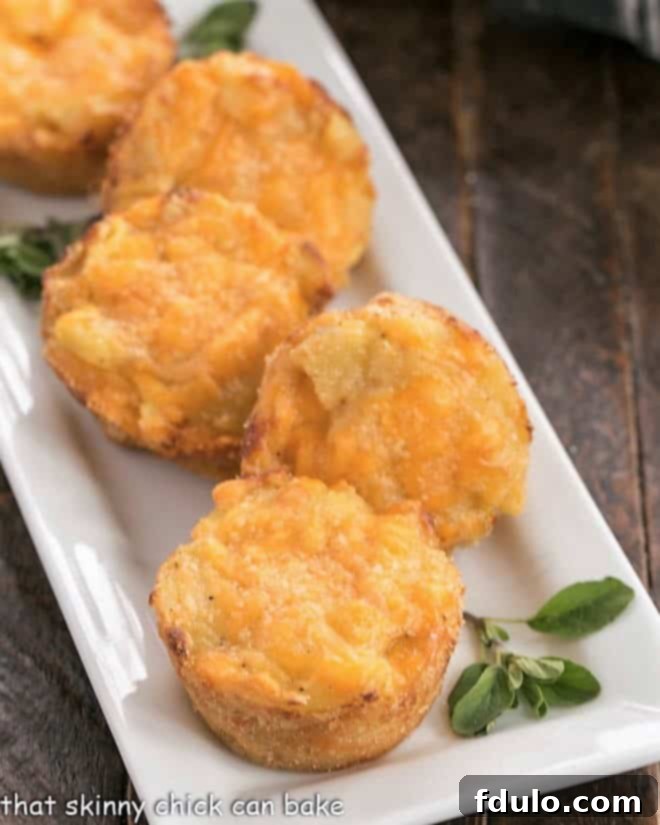 Cheesy Potato Cups - Individual servings of this cheesy potato recipe got rave reviews from my family! Close-up of golden-brown Cheesy Potato Cups on a white serving tray, garnished with fresh herbs.