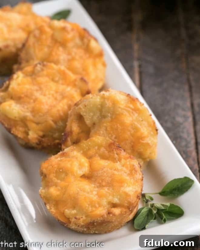 Cheesy Potato Recipe baked in a muffin tin for a delicious side dish that will complement almost any meal Close-up view of two cheesy potato cups on a ceramic platter, garnished with a sprig of fresh oregano.