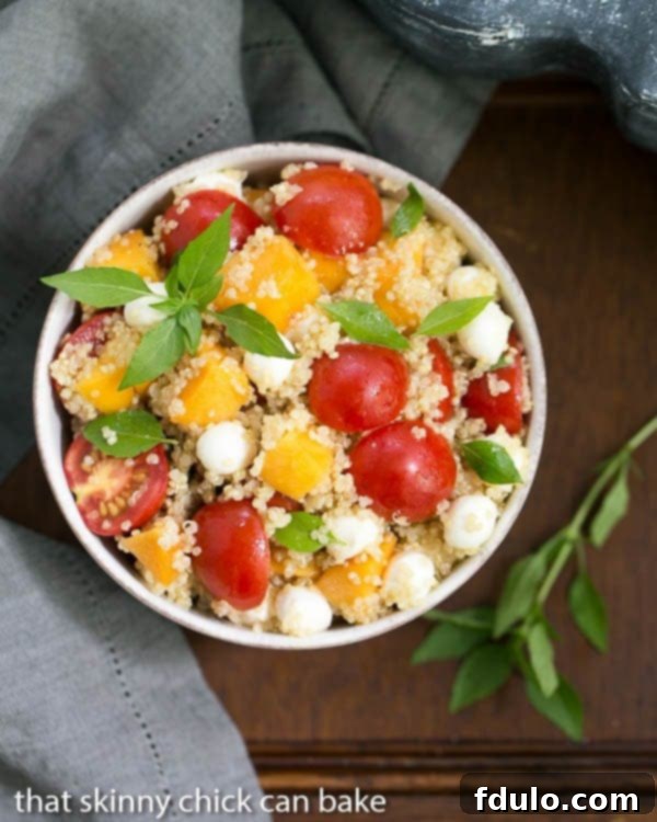 Overhead view of Peach Quinoa Caprese Salad in a white bowl garnished with fresh basil leaves, showcasing its vibrant colors and textures.